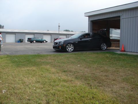 1993 Ford Taurus - A black sedan is parked outside a garage, with other vehicles visible in the background.