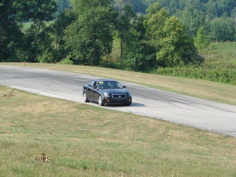 1993 Ford Taurus - A black Cadillac sedan navigates a turn on a road course, displaying the number 86 on its windshield.