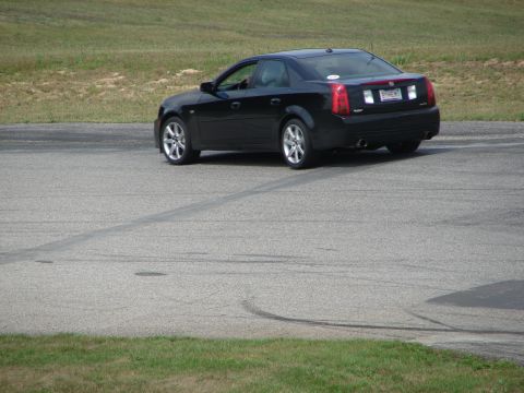 1993 Ford Taurus - A black sedan is seen from the rear on a paved surface, possibly a track, with grass bordering the area.