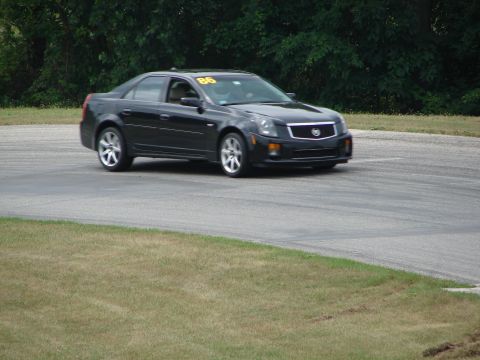 1993 Ford Taurus - A black sedan with a yellow number 86 sticker on its windshield navigates a turn on a road course.