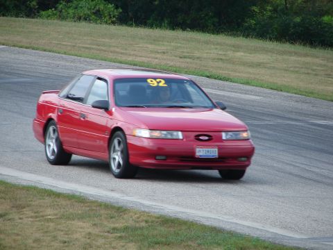 1993 Ford Taurus - A red 1993 Ford Taurus with racing number 92 navigates a turn on a road course.