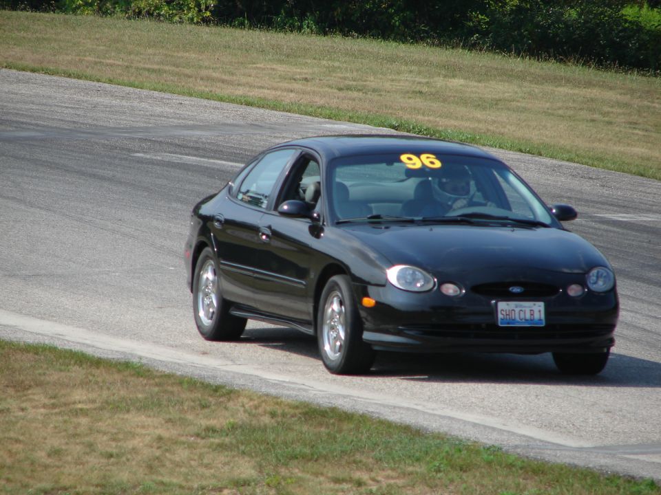 Black sedan with yellow number 96 on windshield driving on a track