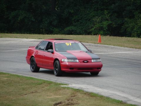 1993 Ford Taurus - 1993 Ford Taurus on a road course, identified by its distinctive body style and grille.