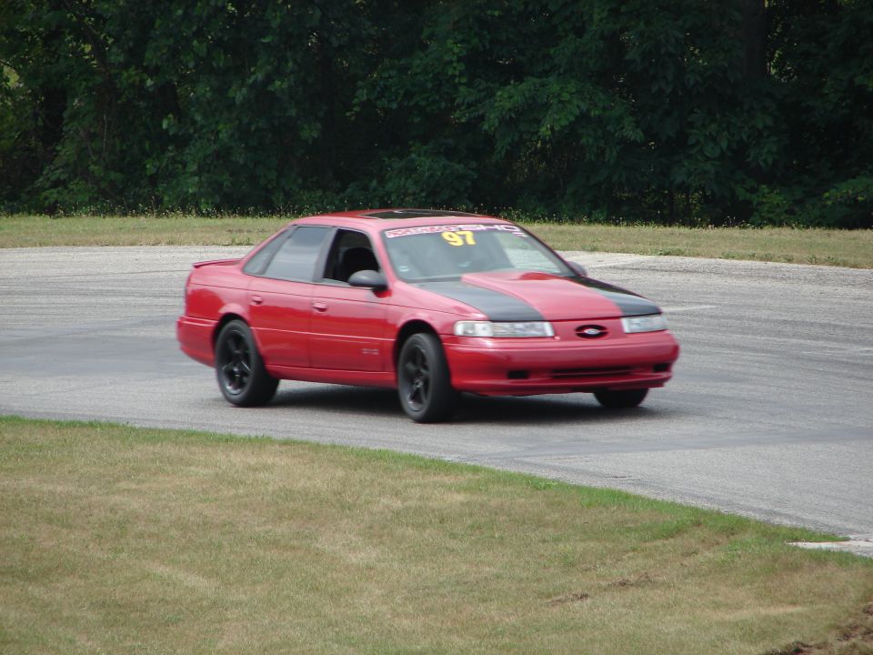 Red sedan with black hood stripes on a race track, number 97 on windshield banner