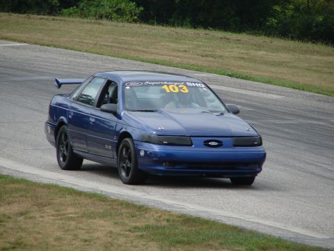 1993 Ford Taurus - Blue 1993 Ford Taurus SHO with racing numbers and a spoiler on a race track.