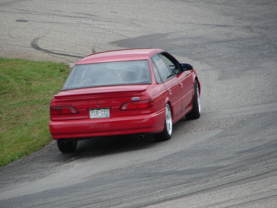 Red 1993 Ford Taurus sedan from rear on a road course