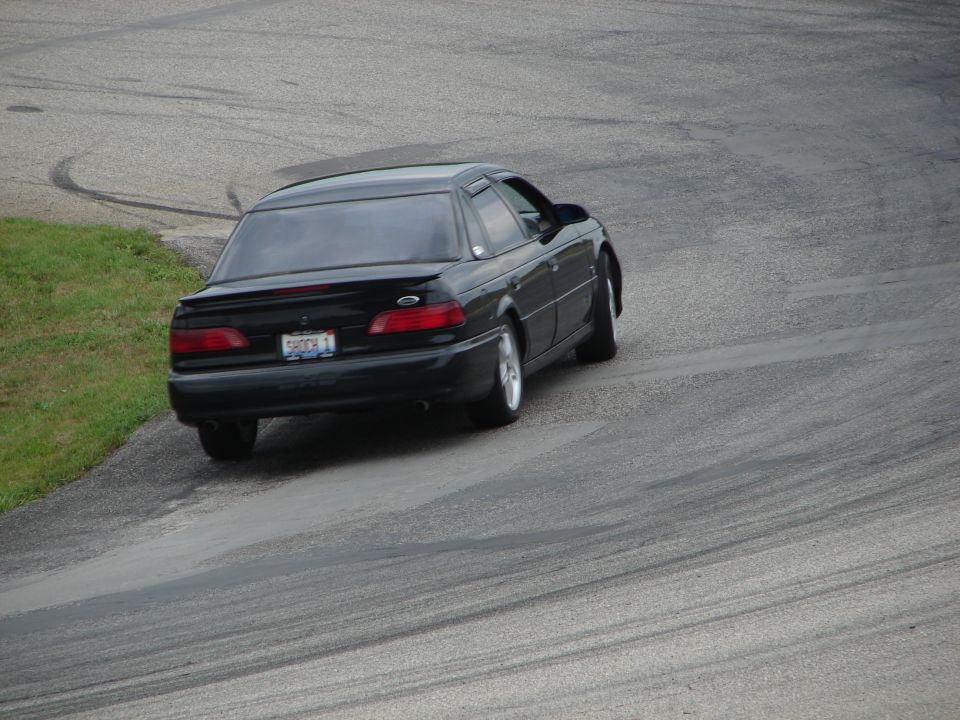 Black 1993 Ford Taurus on a race track, seen from the rear