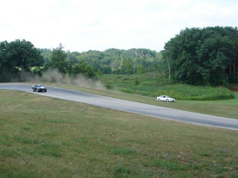 1993 Ford Taurus - Two cars race on a track, with one creating a dust cloud as it turns.