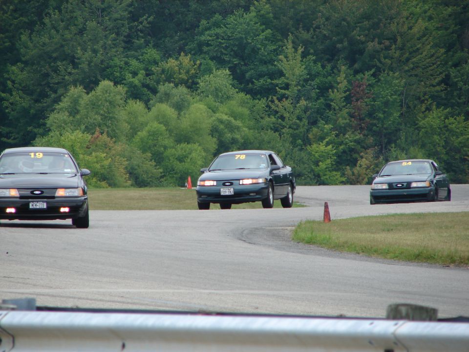 Three dark 1993 Ford Tauruses race on a track, number 78 in the lead