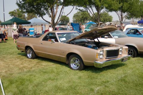 1967 Ford Ranchero - This tan 1977 Ford Ranchero is displayed with its hood open at a car show, alongside other vehicles.