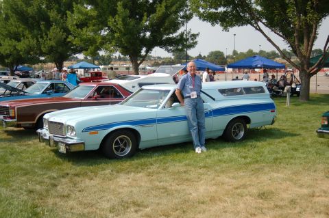 1967 Ford Ranchero - A man poses with his light blue pickup truck, which features a camper shell, at an outdoor car show.