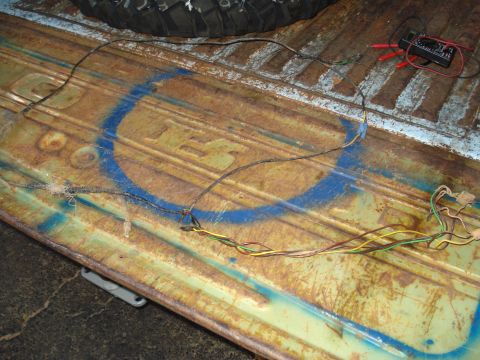 1967 Ford F-250 - Wiring harness and multimeter on a rusty truck bed, with a blue spray-painted circle visible.
