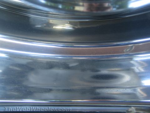 1990 Ford Bronco - Macro view of a polished chrome dually wheel and trim, its mirror surface reflecting distorted surroundings.