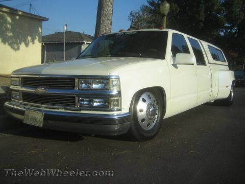 1990 Ford Bronco - White lowered Chevrolet crew-cab dually pickup with billet grille and bowtie emblem, front three-quarter view in a driveway.
