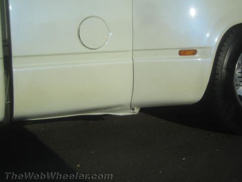 1990 Ford Bronco - Lower rocker panel of a white lowered truck showing the fuel filler door, amber side marker, and a rear tire.