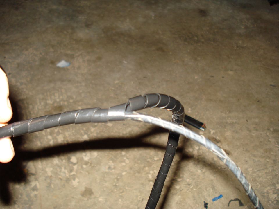 Close-up of a black wire harness with spiral wrap and exposed copper wire