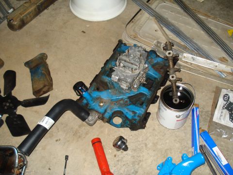 1967 Ford F-250 - Engine block and parts laid out on a concrete floor, including a carburetor, hose, and fan.