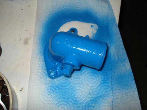 1967 Ford F-250 - Engine part painted bright blue, resting on paper towels with blue spray paint overspray.