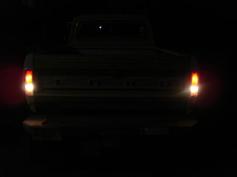 1967 Ford F-250 - The rear of a 1967 Ford F-250 pickup truck is shown at night, with its taillights on.
