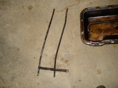 1967 Ford F-250 - Engine oil pan and dipstick tubes are shown on a concrete surface.