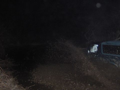 1996 Ford Bronco - A vehicle navigates a muddy area in the dark, with water and mud splashing around it.