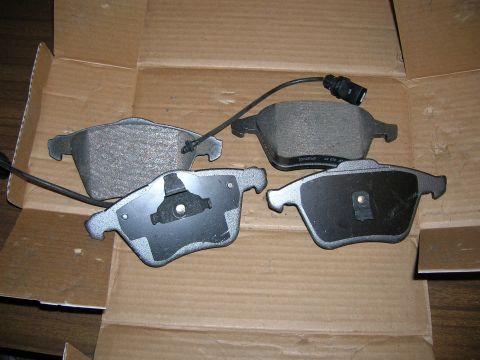 1994 Ford Probe - A set of four brake pads, two with wear sensors, are displayed in a cardboard box.