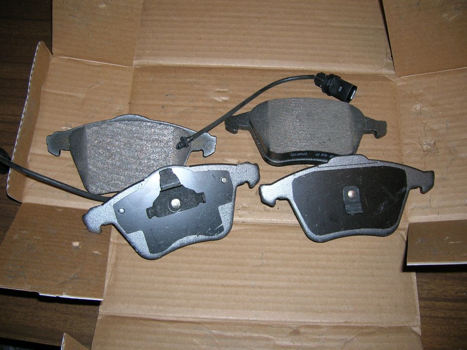 Four brake pads with sensors in a cardboard box