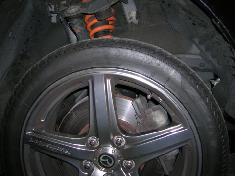 1994 Ford Probe - A close-up view of a vehicle's wheel assembly, including the tire, rim, brake components, and suspension system.