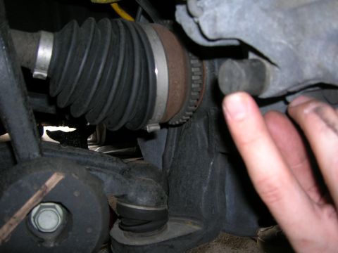 1994 Ford Probe - Close-up view of a CV axle boot and suspension components, with a hand pointing to a part of the assembly.