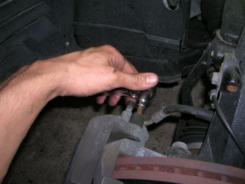1994 Ford Probe - Close-up of a hand using a socket wrench to work on a vehicle's brake caliper.