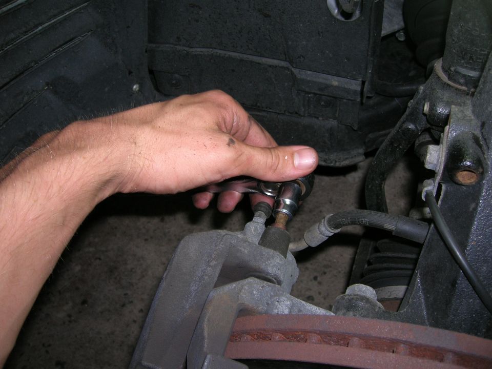 Hand tightening a bolt on a brake caliper with a socket wrench