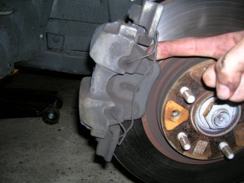 1994 Ford Probe - A mechanic's hand is shown working on a car's brake caliper and rotor assembly.