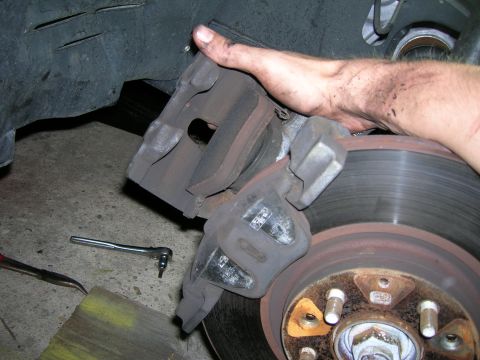 1994 Ford Probe - A mechanic is shown replacing a car's brake caliper and rotor.