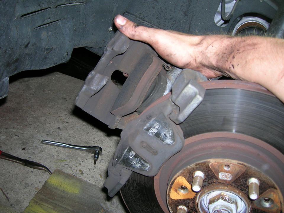 hand holding car brake caliper near rotor