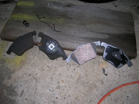 1994 Ford Probe - Several brake pads are laid out on a concrete surface, with a wooden plank behind them.