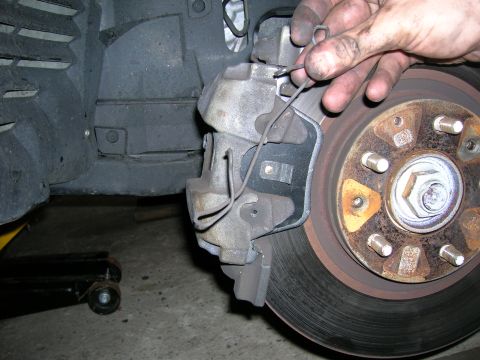 1994 Ford Probe - Mechanic's hands adjusting a brake caliper over a rusty rotor.