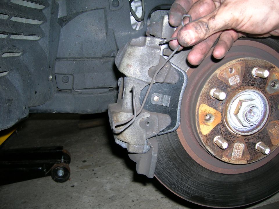 Close-up of a brake caliper being worked on, with a rotor visible