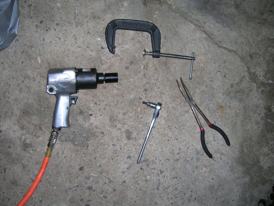 Air impact wrench, C-clamp, socket wrench, and long-nose pliers on concrete floor