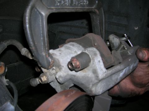 1994 Ford Probe - A close-up view of a brake caliper being compressed by a C-clamp.