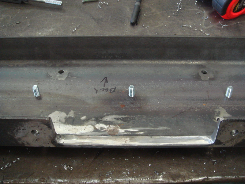 Metal bracket with four bolts and an arrow pointing up labeled 'Back'