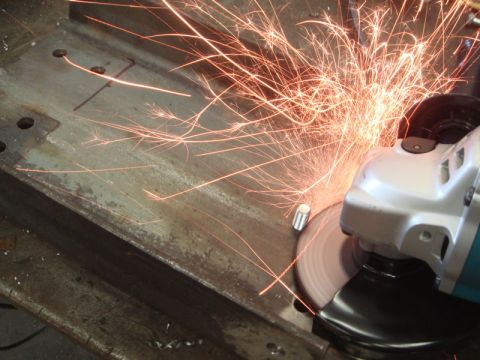 1996 Ford Bronco - An angle grinder is used to cut through a metal beam, creating a shower of sparks.