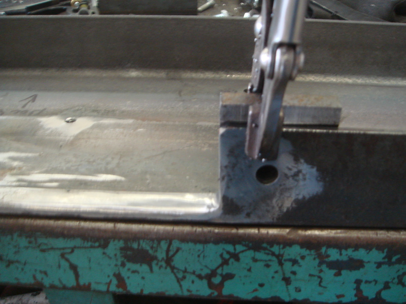 Metal frame with a clamp holding a small piece of metal