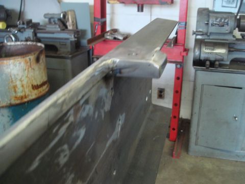 1996 Ford Bronco - A metal bracket is shown in a workshop, possibly for a winch installation, with various tools and machinery in the background.