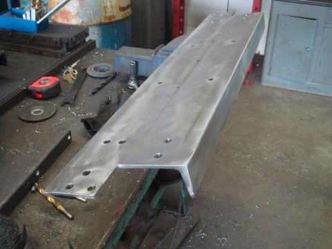 1996 Ford Bronco - Metal bracket with holes on a workbench, surrounded by tools and metal shavings.