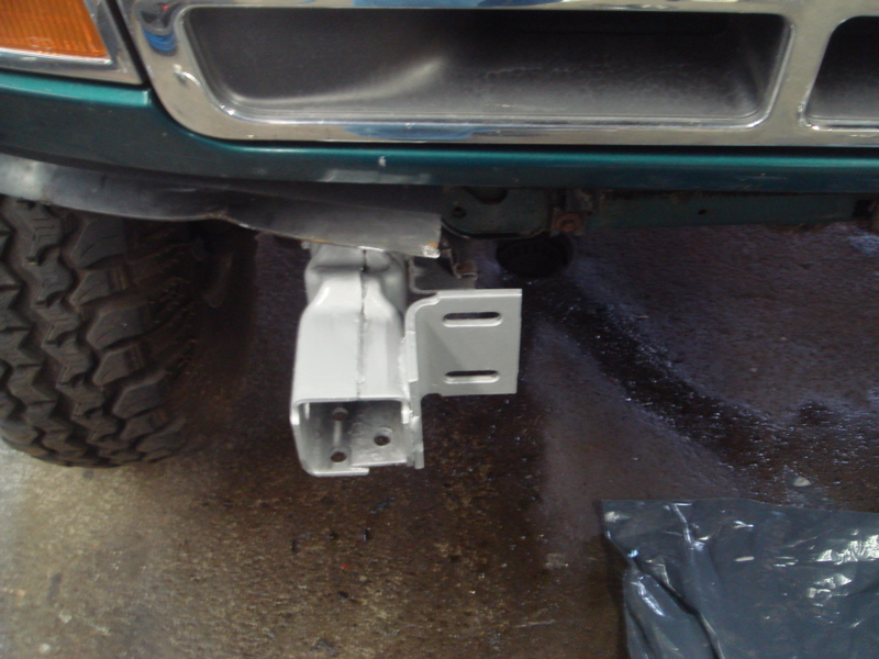 Close-up of a custom winch mount bracket being installed on a vehicle's front end