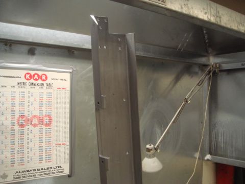 1996 Ford Bronco - A metal bracket is mounted on a wall next to a metric conversion table.