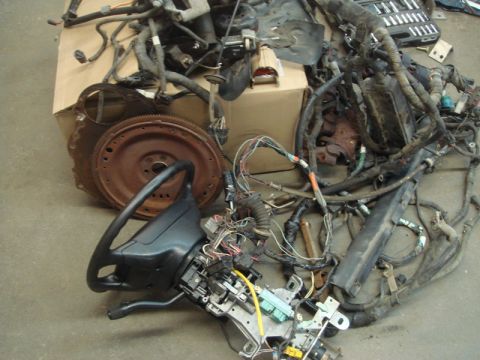 1996 Ford Bronco - A collection of automotive parts, including a steering column and wiring, are laid out on a concrete surface.