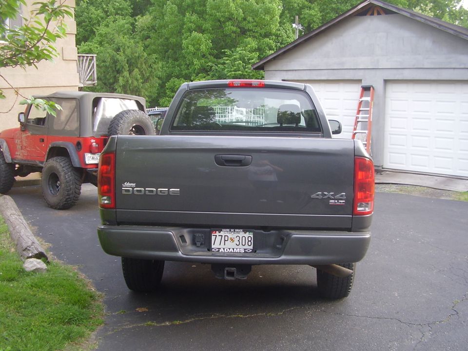 Dark gray Dodge Ram 1500 pickup truck rear view, license plate 77P 308, with a red Jeep Wrangler parked to its left