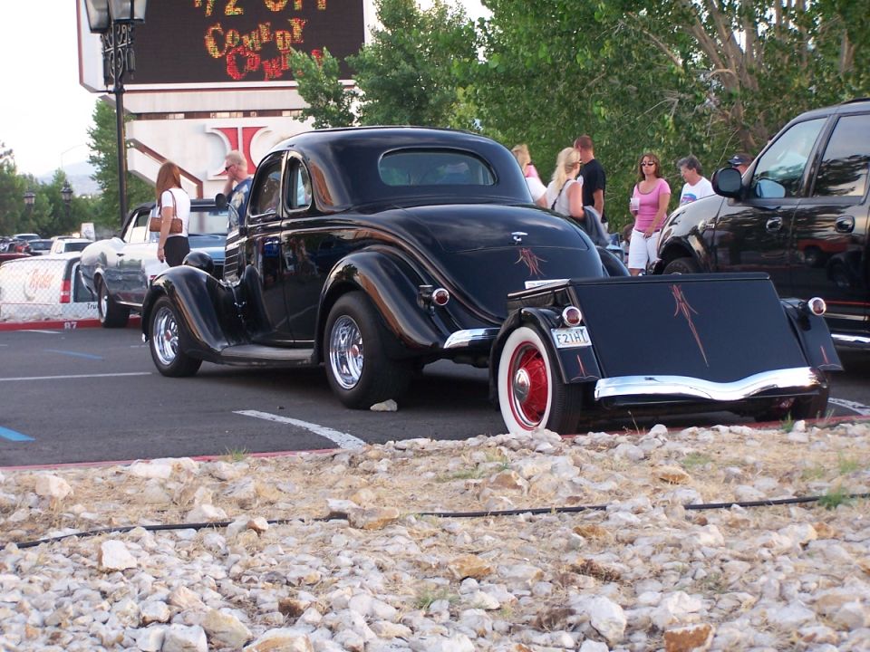 Black hot rod coupe with pinstripes and trailer, rear view. License plate E21HL