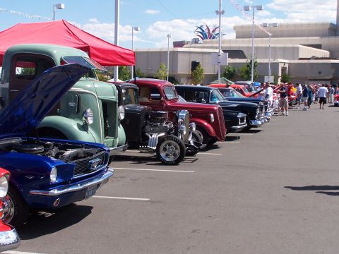 1990 Ford Bronco - Classic cars are lined up at an outdoor event, with spectators milling around in the background.